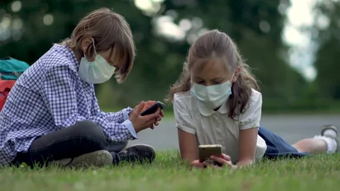Cute pupils using smartphones at the elementary school. Boy and girl in safety Stock Footage 136355477