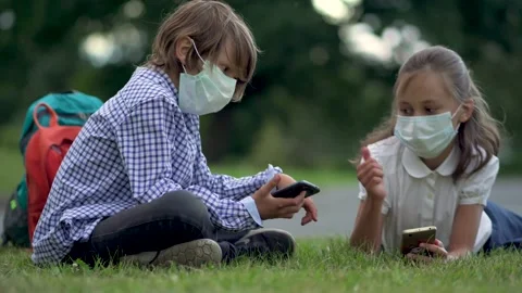 Cute pupils using smartphones at the elementary school. Boy and girl in safety Stock Footage 136359938