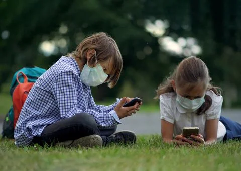 Cute pupils using smartphones at the elementary school. Boy and girl in safety Фото