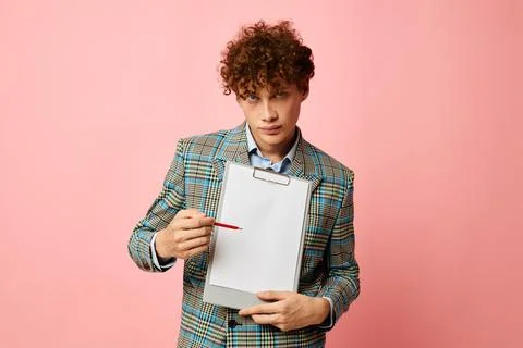 Cute red-haired guy folder for papers blank sheet posing in suit pink background Stock Photos