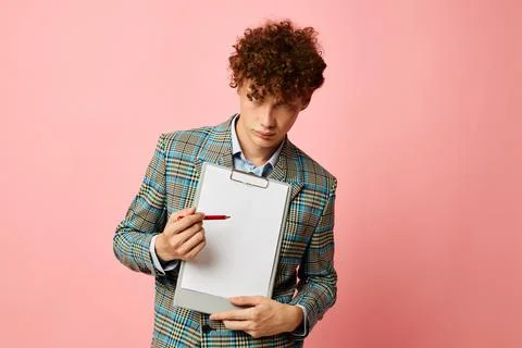 Cute red-haired guy folder for papers blank sheet posing in suit pink background Stock Photos