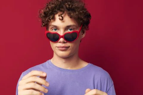 Cute red-haired guy hand gestures heart shaped glasses posing red background Stock Photos
