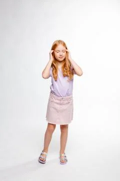 Cute red-haired long-haired girl in daily clothes put her hands to her temple Foto stock