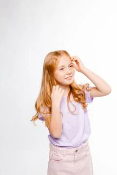 Cute red-haired long-haired girl in daily clothes (skirt, t-shirt) Stock Photos