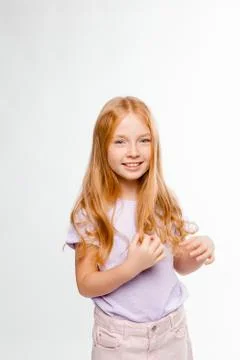 Cute red-haired long-haired girl in daily clothes (skirt, T-shirt) braids her Stock Photos