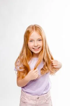 Cute red-haired long-haired girl in daily clothes (skirt, T-shirt) braids her Foto stock