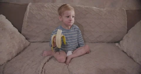 Cute Red Haired Toddler Eating a Banana Stock Footage 341883536