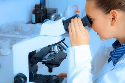 Cute researcer using microscope - background is blue toned Stock Photos