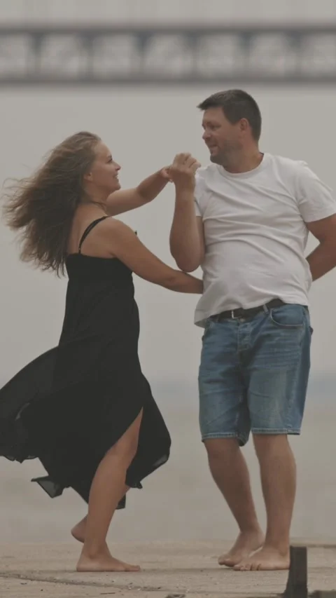A cute romantic married couple dancing on the pier with a bridge on the Vídeo Stock 329217396