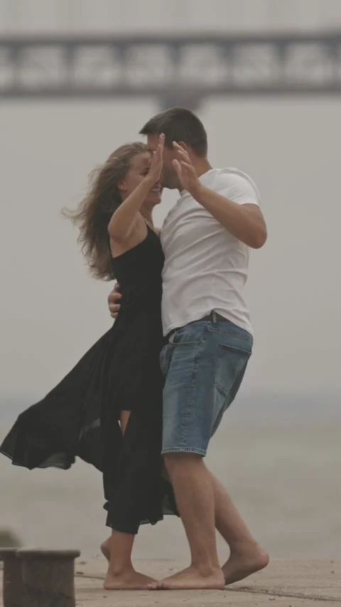 A cute romantic married couple dancing on the pier with a bridge on the Stock Footage 329217400