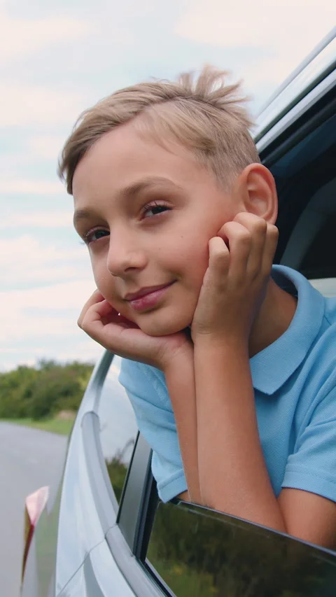Cute satisfied smiling 10-year-old boy puts his head out of the auto window and  Stock Footage 329436005