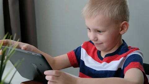 Cute school boy child learning or playing on computer tablet pc, distance Stock Footage 130551503