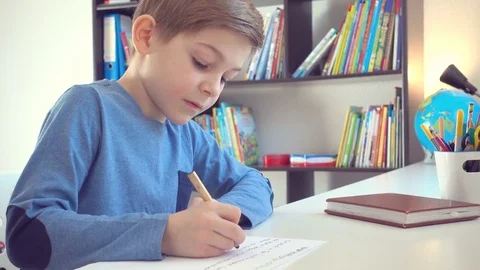 Cute school boy doing homework at desk Stock Footage 72322341
