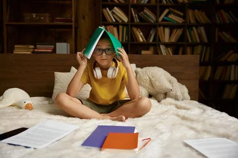 Cute school boy having difficulties with homework sitting in bed Stock Photos