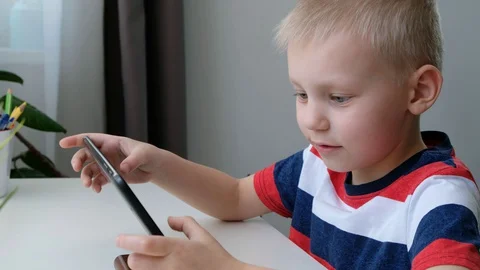 Cute school boy learning or playing on computer tablet pc, distance education Stock Footage 128976440