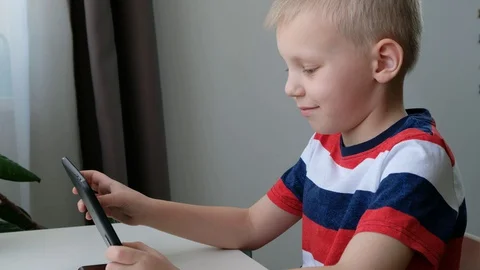 Cute school boy learning or playing on computer tablet pc, distance education co Stock Footage 129485904