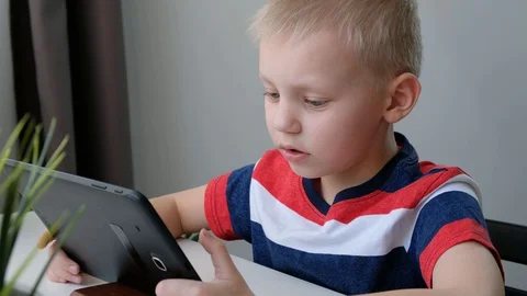 Cute school boy speaking with someone via voice call, learning on computer Stock Footage 129020477