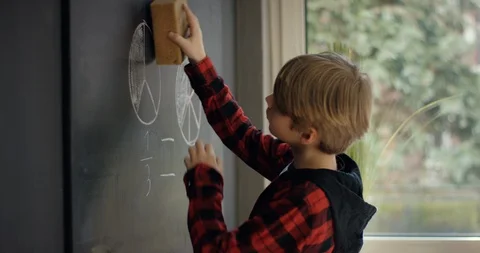 Cute Schoolboy cleaning blackboard with a duster in classroom Video stock 128903373