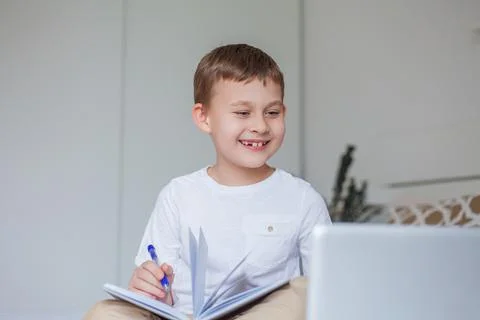 Cute schoolboy doing homework on the bed. A little boy of 7 years old is doin Foto stock