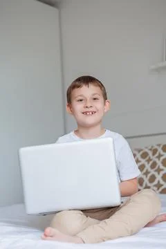 Cute schoolboy doing homework on the bed. A little boy of 7 years old is doin Stock Photos
