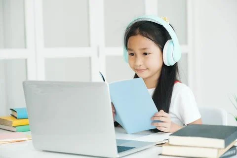 Cute schoolboy looking at notebooks studying and writing notes at home covid-19 Stock Photos