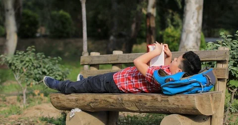 Cute schoolchild with book at the spring nature Stock Footage 105472186