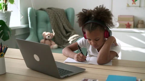 Cute schoolgirl writing and studying in front of laptop while sitting at table Stock Footage 172150053
