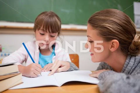 Cute schoolgirl writing a while her teacher is talking Stock Photos