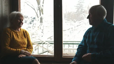 Cute senior couple sitting on window-sill and talking happily medium shot indoor Vídeo Stock 199322541