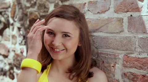 Cute shy brunette posing by a brick wall. High definition video. Stock Footage 49479886
