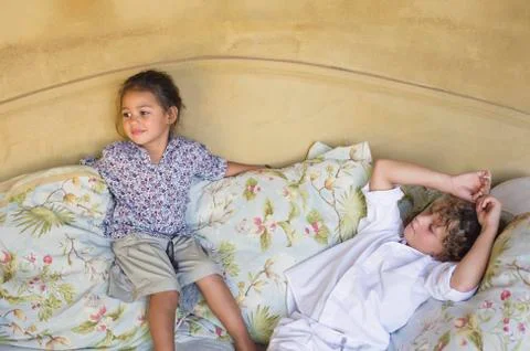 Cute siblings lying on couch at home Stock Photos