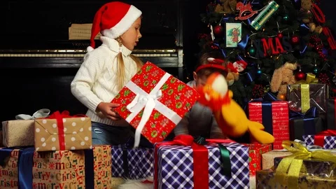 Cute siblings open up big wrapped present boxes to play with surprise Christmas Stock Footage 99037139