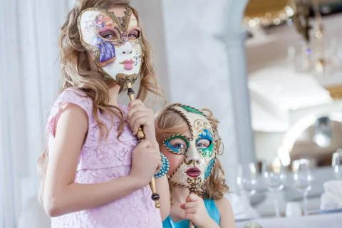 Cute sisters posing hiding faces behind masks Stock Photos