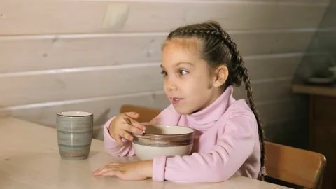Cute small 5 years old girl sitting at dining table in country house kitchen Stock Footage 220917760