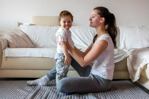 Cute small boy with Down syndrome playing with mother in home Stock Photos