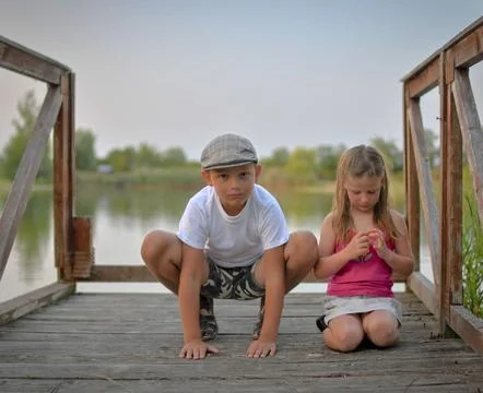 A cute small boy with a flat cap and a sweet little girl are sitting on a w.. Stock-Fotos