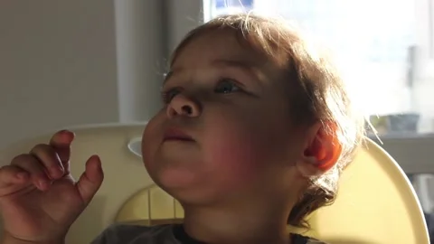 Cute small boy interested watching TV cartoons in the kitchen on a sunny day Video stock 123072902