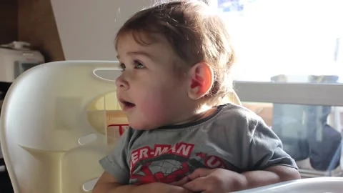 Cute small boy interested watching TV cartoons in the kitchen on a sunny day Video stock 123072924