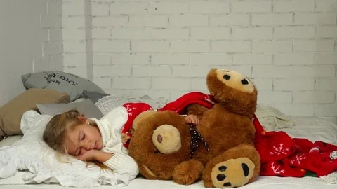Cute small daughter sleeping with stuffed bear receiving wonderful wrapped Stock Footage 98688060
