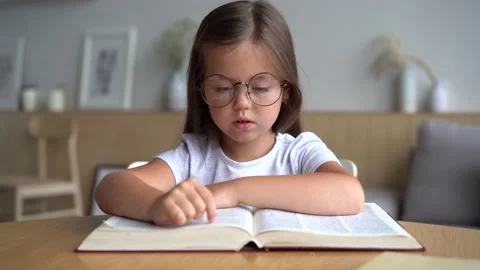 Cute smart primary school child girl reading book at home table Stock Footage 139209687