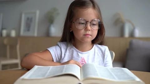 Cute smart primary school child girl reading book at home table Stock Footage 139209760