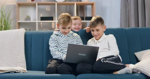 Cute smiling 2-aged boy standing behild the couch on which sitting his eldest Video stock 151912634