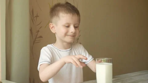 Cute smiling boy drinks milk from a high transparent glass Stock Footage 63563389