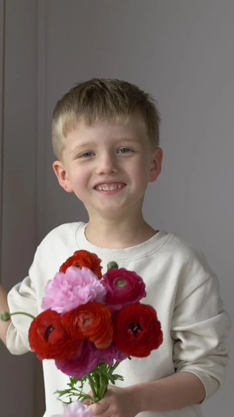 Cute smiling boy holding bright flower bouquet for Mothers Day or teacher Stock Footage 335144486