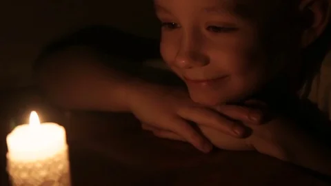 A cute smiling boy looking at a burning candle Stock Footage 73437797