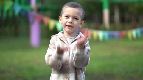 Cute smiling boy in plaid jacket performs the viral six seven meme hand gesture Stock Footage 345285688