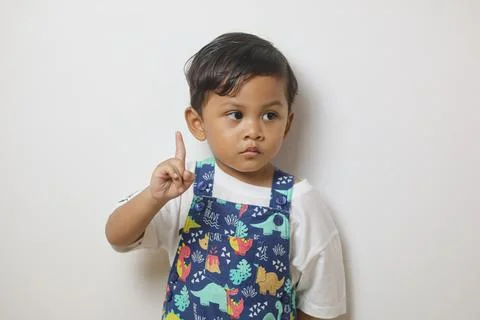 Cute smiling boy in plain white t shirt looking and pointing hand up in iso.. Stock Photos