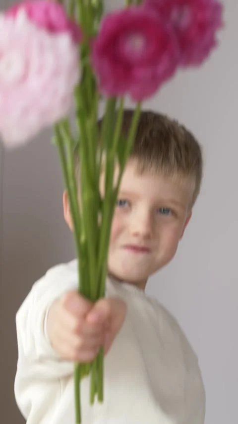 Cute smiling boy presenting bouquet high toward viewer with joyful confident 스톡 동영상 335144285