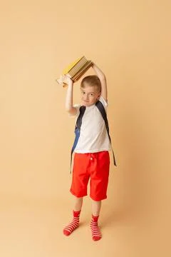 Cute smiling child with a backpack holding books in preparation for school Stock Photos