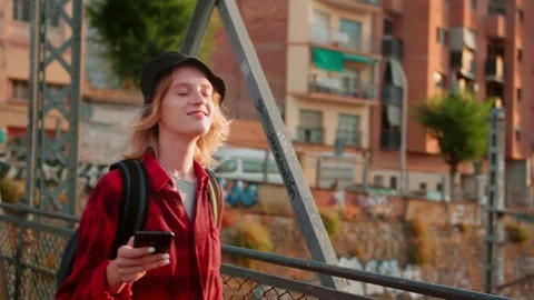Cute smiling female student going to studies with mobile phone in hand at Stock Footage 115910429